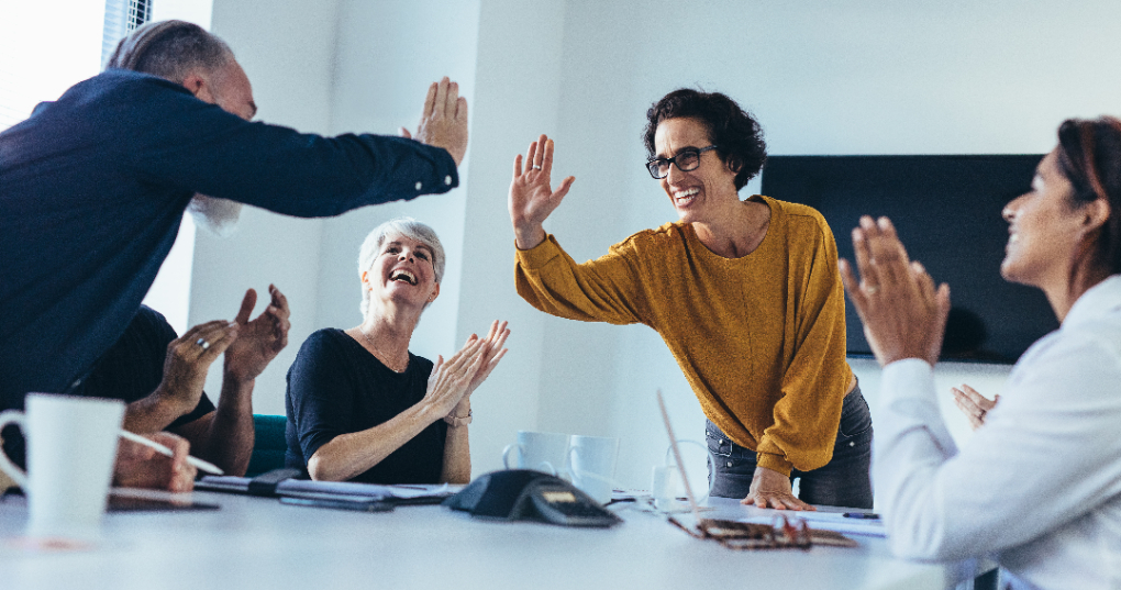 Coworkers high-fiving across a conference room table