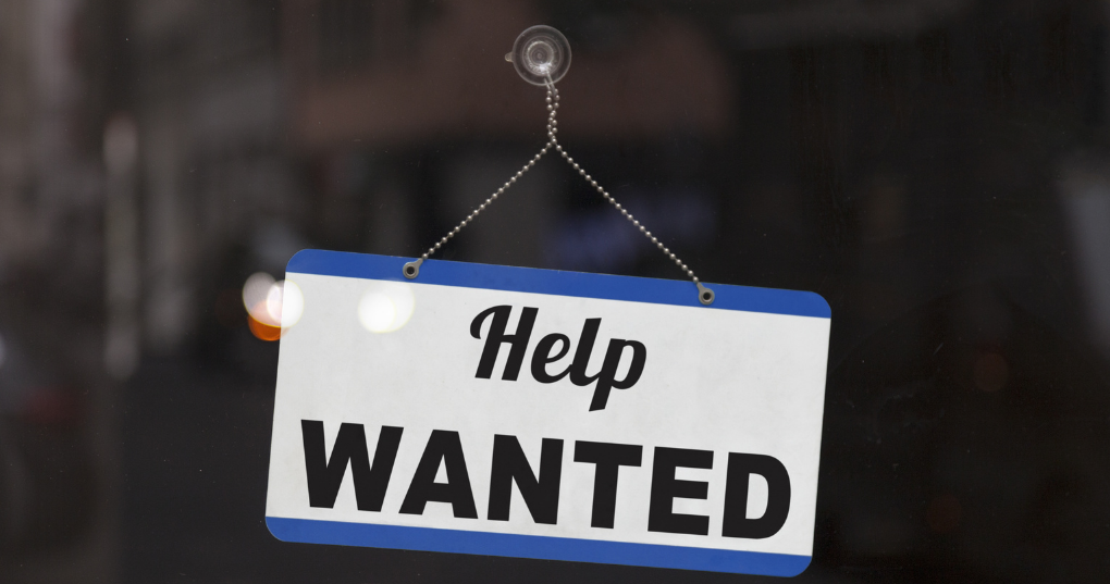 A help wanted sign hanging on a door