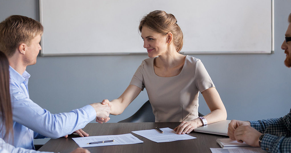 Woman shaking man's hand in office.