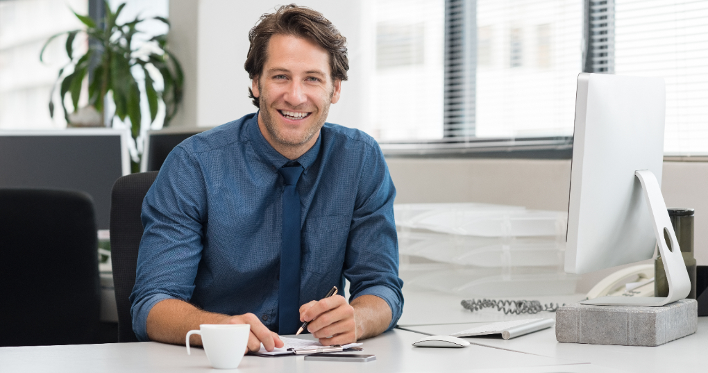 A man smiling while sitting at his desk